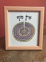Front view showing framed print with Hebrew text and spiral design