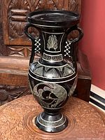 Front view of black and cream Greek ceramic vase showing classical motifs and twin handles