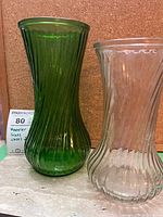 Green and clear ribbed swirl vases side by side showing overall shape and color contrast