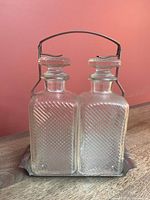 Front view of both decanters set in metal caddy