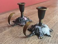 Both candlesticks angled side view showing curved handles, bases, wax residue