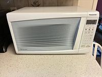 Front view of white Panasonic microwave oven showing door and control panel