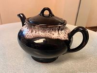 Full side view of teapot showing glaze pattern, handle, spout, lid