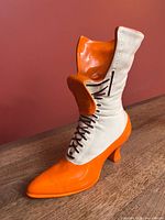 Front-left view of orange and white ceramic boot planter