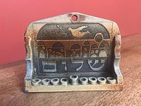 Front view showing relief scene, nine candle holders, dove and Hebrew text