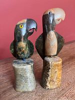 Front view of both stone parrots on marble bases showing color and detail