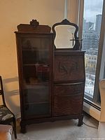 Front view showing entire cabinet with glass door, mirror, carved details