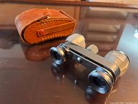 Opera glasses front view beside case