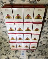 Stack of 16 boxed Hallmark ornaments front view