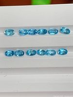 Twelve oval blue topaz stones aligned in two rows