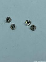 Four loose round brilliant diamonds on light background