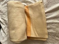 Blanket rolled and folded showing cream surface and striped edge