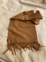 Full view of camel wool scarf laid flat showing fringe