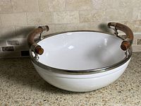 Top view of white porcelain serving bowl showing wood handles and metal rim