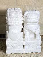 Front view of both white stone guardian lion statues side by side