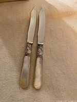 Full view of both butter spreaders showing blades, ferrules, and handles