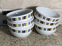 Six white stoneware bowls stacked showing geometric band