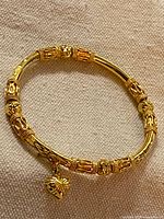 Full view of circular gold-plated bangle with charm