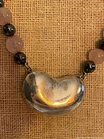 Close-up of kidney-shaped sterling pendant with adjacent beads