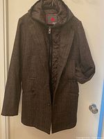 Front view of Blue Guru brown herringbone overcoat hanging on door, showing overall style and removable hooded liner