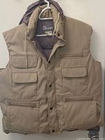 Front view of tan hooded puffer vest showing pockets and closure