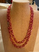 Full view of doubled pink glass bead necklace on bust form