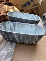 Two grey and white marble-effect oval planters on cardboard
