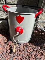 Front view of grey metal butter churn with red accents and crank