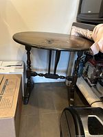 Full view of antique oval drop-leaf table showing folded leaves and turned legs