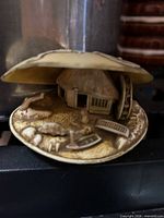 Overall view of carved diorama showing shell casing, hut, animals and accessories