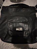 Front view of black Coach leather purse showing pocket with turn-lock clasp and overall condition