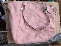 Front view of pink Coach pebbled leather shoulder bag with hangtag and handles