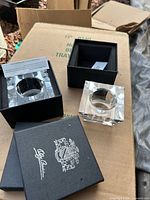 Two crystal tea light holders inside black Oleg Cassini boxes with inserts