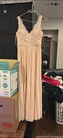 Full view of blush floor-length dress on hanger