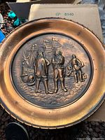 Front view of round embossed copper plate showing nautical relief scene