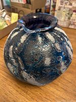 Front view of round blue-silver art glass vase