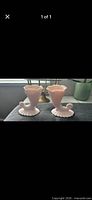 Pair of opaque pink fluted bud vases with scalloped bases and scroll accents displayed side by side