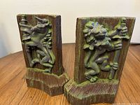Pair of textured brown and green mythical creature bookends on wood surface