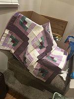 Overall view of the patchwork throw quilt draped over stairs showing log cabin pattern and color scheme