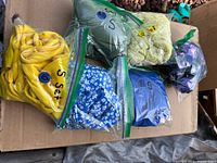 Six zipper bags each containing a small size bikini in various colors on cardboard surface