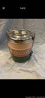Full view of assembled three-tier tiffin showing stainless lid, beige middle tier with chevron design, green bottom tier, and locking handle
