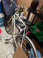 Left side view of white 10-speed bicycle leaning against shelving