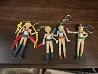 Four Sailor Moon series figural keychains laid on dark surface