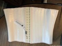 Full view of beige waist trainer laid flat showing hook closure and hang tag