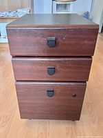 Front view showing three drawers with recessed pulls and lock
