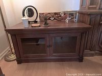 Front view of brown solid wood TV stand with glass doors