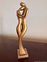 Front view of gold resin embracing couple sculpture on square base