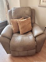 Front view of taupe leather power recliner with two throw pillows
