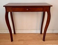 Front view of brown wood entry table showing drawer and curved legs