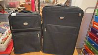 Front view of both black American Tourister soft-sided suitcases